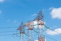 Red white electricity pylons, blue sky with white clouds