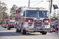 A red and white firetruck driving in a Christmas parade