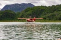 Red and white float plane taxiing on a lake