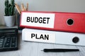 Red and white folders with documents lying on the desktop next to a calculator and a pen. The lettering on the folder has