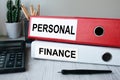 Red and white folders with documents lying on the desktop next to a calculator and a pen. The lettering on the folder has