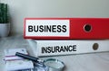 Red and white folders with documents lying on the desktop next to a calculator and a pen. The lettering on the folder has