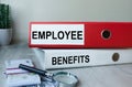 Red and white folders with documents lying on the desktop next to a calculator and a pen. The lettering on the folder has