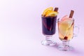 Red and white glogg or mulled wine with orange and apple slices and cinnamon stick on pink background, horizontal, copy space