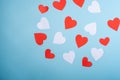 Red and white handmade paper hearts valentines on blue background