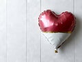 A red and white heart shaped foil balloon hanging on a wall Royalty Free Stock Photo