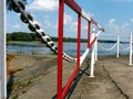 red and white with heavy chain and gate in diminishing perspective at a river side
