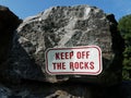 Red and white keep off the rocks sign on grey boulder Royalty Free Stock Photo