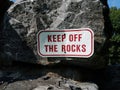 Red and white keep off the rocks sign on grey boulder Royalty Free Stock Photo