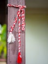 Red and white knitting string tied up on house wooden pillar martisor romanian 1st of march celebration concep