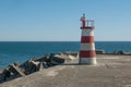 Red and white light house at end of harbour wall in Povoa de Varzim, Portugal Royalty Free Stock Photo