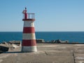 Red and white light house on breakwater wall in Povoa de Varzim, Portugal Royalty Free Stock Photo