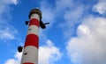 Red and white lighthouse against blue sky with clouds. Royalty Free Stock Photo