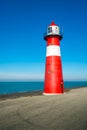 Red and white lighthouse against a bright blue sky Royalty Free Stock Photo