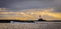 A red and white lighthouse on an island surrounded by storm clouds