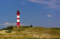 Red and white lighthouse on a sand dune lightly covered with beach grass in front of a blue sky Royalty Free Stock Photo