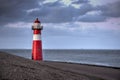 A red and white lighthouse at sea at dusk near Zeeland, Netherlands. Royalty Free Stock Photo