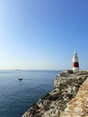 Red and White Lighthouse Stands Guard as Sailing Boat Travels by