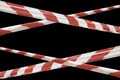 Red and white lines of barrier tape prohibit passage, tape on black isolate background