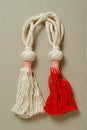 Red and white Martisor, Martenitsa tassel symbolizing springs arrival on beige isolated background. Traditional Moldavian,