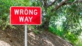 A red and white metal sign saying `Wrong Way` in the woods with copy space Royalty Free Stock Photo