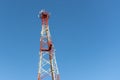 A red and white mobile or cell phone telecommunications tower on a blue sky background looking up Royalty Free Stock Photo