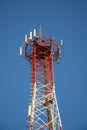 A red and white mobile or cell phone telecommunications tower on a blue sky background looking up Royalty Free Stock Photo