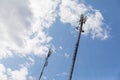 Red and white mobile phone cell tower repeater, with a small microwave dish on blue sky with clouds background Royalty Free Stock Photo