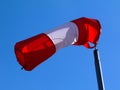 Red and white nylon textile tube windsock blown by the wind Royalty Free Stock Photo