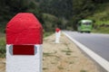 Red and white painted milestones in range on a country road