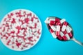 Red white pills or capsules on a plate and in a spoon Royalty Free Stock Photo