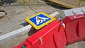 Red and white plastic road fences, road sign `Pedestrian crossing` and warning light