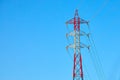 Red and white pole of a high voltage power line with wires and insulators against a bright blue sky. Diagonal arrangement of wires Royalty Free Stock Photo