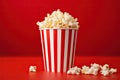 Red and white popcorn box on a red backdrop. Generative AI