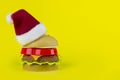 Red-white Santa hat on Plastic hamburger christmass tree on yellow background. Christmas burgers. 2021 New Year sign