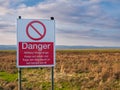 A red and white sign in English warns the public to keep out of land designated for use as a military firing range. Royalty Free Stock Photo