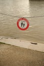 Red and white sign with a message of no access in front of a dirty body of water