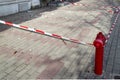 Red white signal tape encloses a part of the sidewalk with construction debris during the repair of an old building. Beware of