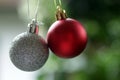 Red and white silver Christmas ball ornament hanging on a blur green tree bokeh light background. Christmas ornament background. Royalty Free Stock Photo