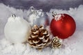 Red White and Silver Christmas Ornaments and a Pinecone on a Snowy Background. Royalty Free Stock Photo