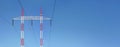 Red and white steel power pylon construction with high voltage cables against blue sky. Wide banner for electric energy industry Royalty Free Stock Photo