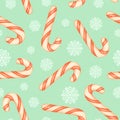 Red and white striped candy canes and white snowflakes on a blue background. Christmas seamless pattern with candy canes and Royalty Free Stock Photo