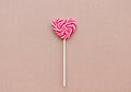 Red sweet lollipop in the shape of a heart on a craft background