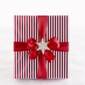 Red and white striped Christmas gift present with metallic wrapping paper, satin ribbon bow and silver glitter snowflake Royalty Free Stock Photo