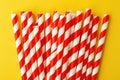 Red and white striped drinking straws on a yellow background Royalty Free Stock Photo