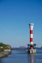 Red-white striped lighthouse with Hamburg harbor in the background during spring and with blue sky