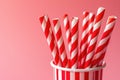 Red and white striped paper straws in a matching striped cup on a pink background Royalty Free Stock Photo