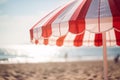 Red and white striped sun parasol with blurry beach in background Royalty Free Stock Photo