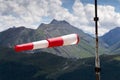 Red and white striped windsock dramatic clouds mountains in background Royalty Free Stock Photo