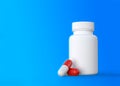 Red-white tablets with a pharmacy bottle on a blue background Royalty Free Stock Photo